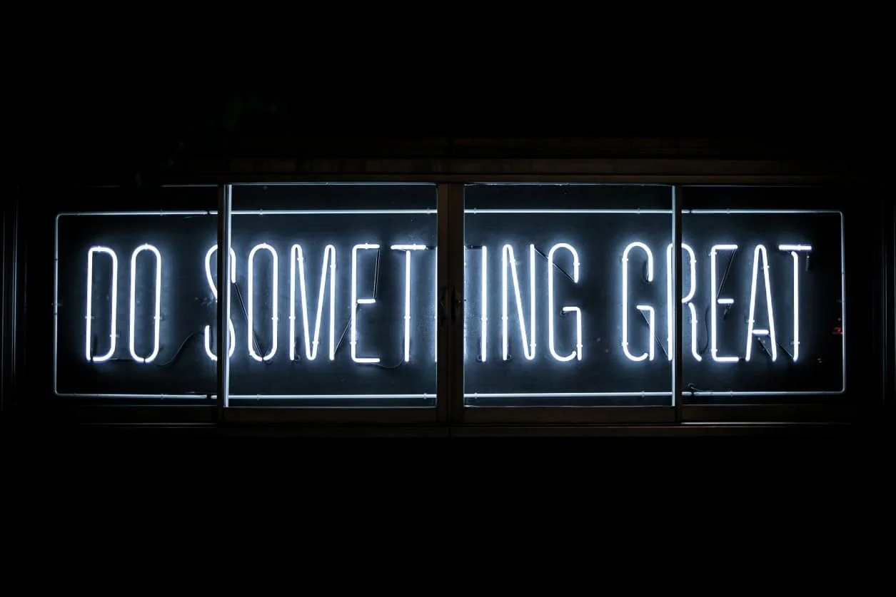 A white neon sign that says 'Do something great'