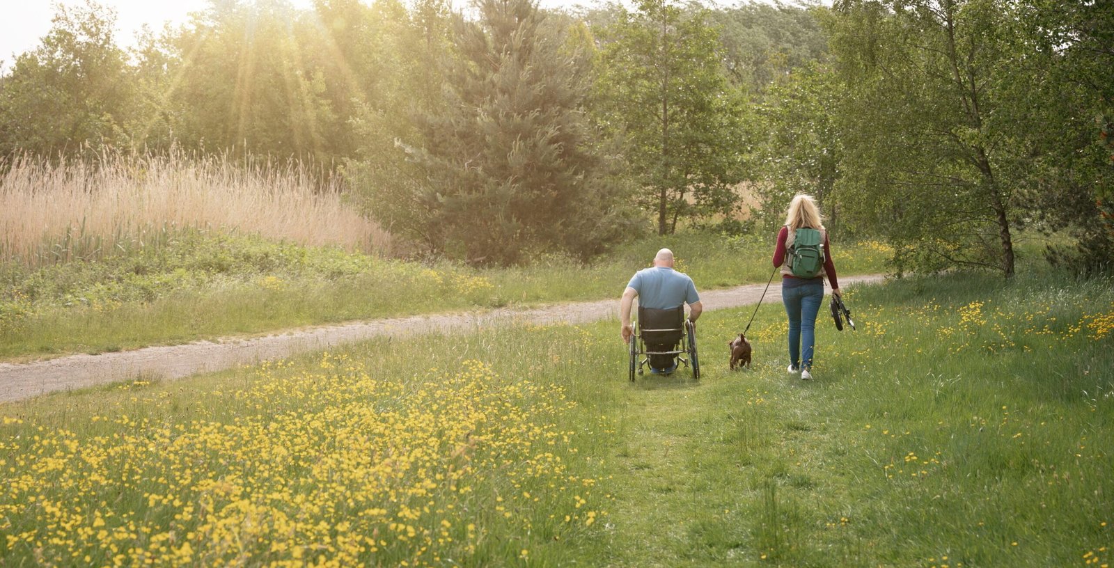 A man in a wheelchair and his friend going across a field