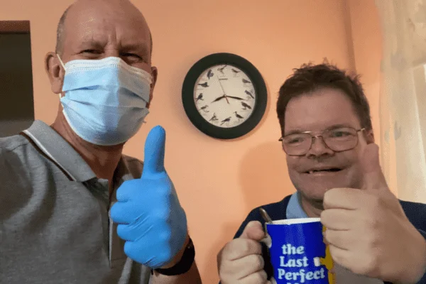 A care user and an abbots care worker taking a selfie with their thumbs up