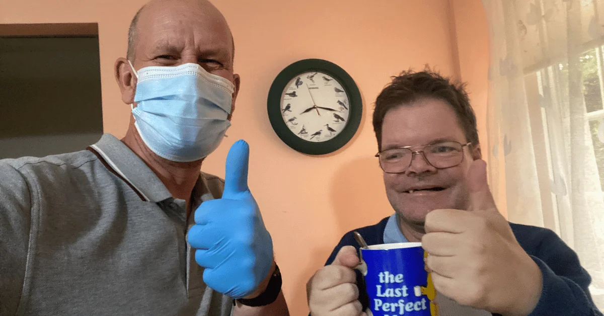 A care user and an abbots care worker taking a selfie with their thumbs up