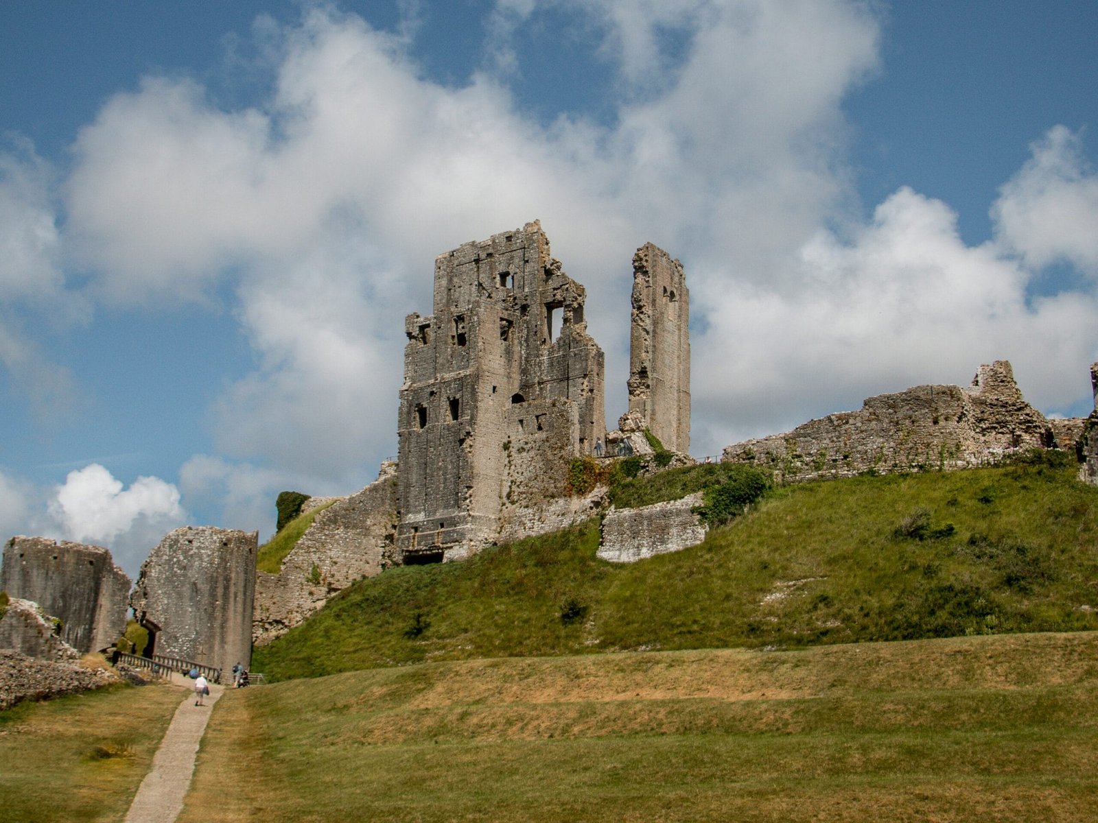 A view of Corfe Castle, in Dorset, looking up from the bottom of the hill to the castle perched atop it.