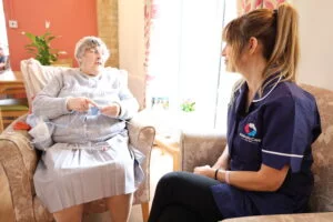 Abbots Care care worker talking to client knitting