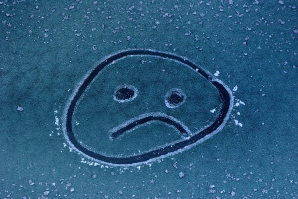 Seasonal affective disorder - sad face drawn into ice on a car window