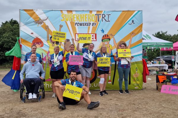 Group of Abbots Care team members smiling at the finish line of the Superhero Triathlon